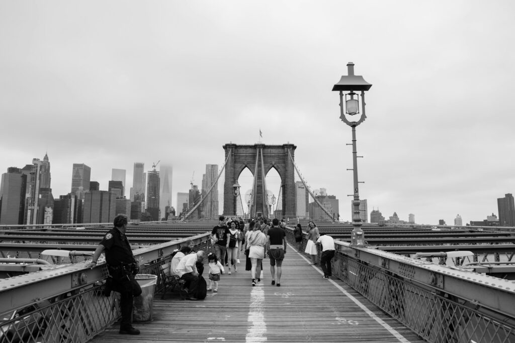 grayscale photography of people walking on bridge